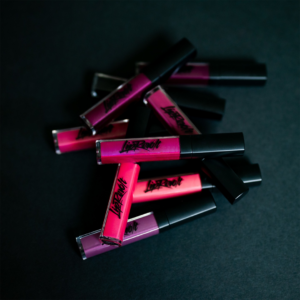 Many different colors of LipRevolt liquid lipstick in a pile on a dark background