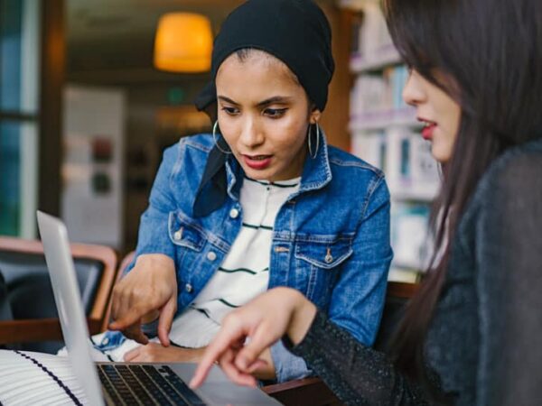 Female business owners exploring grants for women entrepreneurs on a laptop.