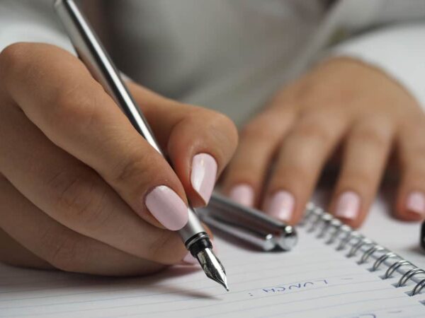 Close of a women's hands, writing notes pertaining to small business loans for women.